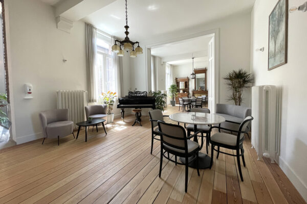 Een andere assistentiewoning in Angelahof, met houten vloeren. De foto is genomen vanuit de woonruimte, waar een piano staat, met toegang tot de eetkamer.