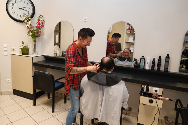 De kapsalon van woonzorgcentrum Borsbeekhof in Borgerhout, waar het haar van een mannelijke bewoner wordt geknipt door de kapper, terwijl hij zichzelf in de spiegel kan zien.