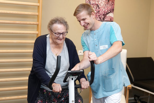 L'Arche de Vie - Façade - Personne âgée sur vélo d'appartement avec kiné - maison de repos Charleroi