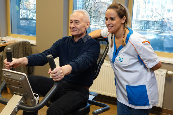 Les Pléiades - un homme âgé sur un vélo d'appartement avec une kiné - Maison de repos - Woluwe St Lambert