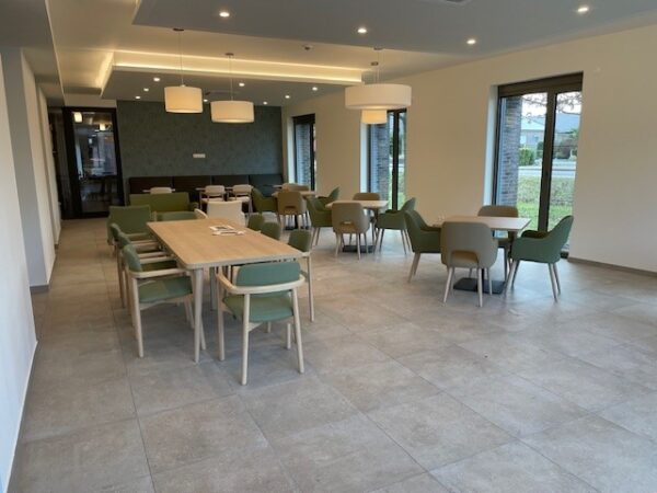 Het Grand Café, met een betegelde vloer en stoelen in groene en beige tinten.