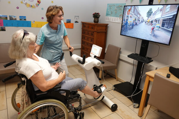 Le Chenoy - Salle de kiné une femme âgée pédale sur un vélo d'appartement - maison de repos Ottignies