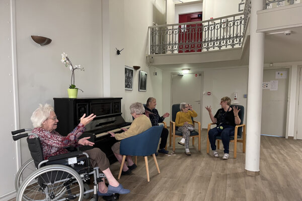 Le Progrès - Hall avec un groupe de peronnes âgées qui chantent et jouent du piano - Maison de repos - La Louvière