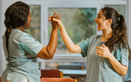 Twee goedlachse collega's bij Korian geven elkaar een high five